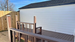 A wooden deck with a railing, a white garage door, and a wooden fence in the background. - My family’s little nest, where our kids grew. (Perryton)
