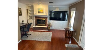 A living room with a fireplace, a dining area, and a TV. - My family’s little nest, where our kids grew. (Perryton)