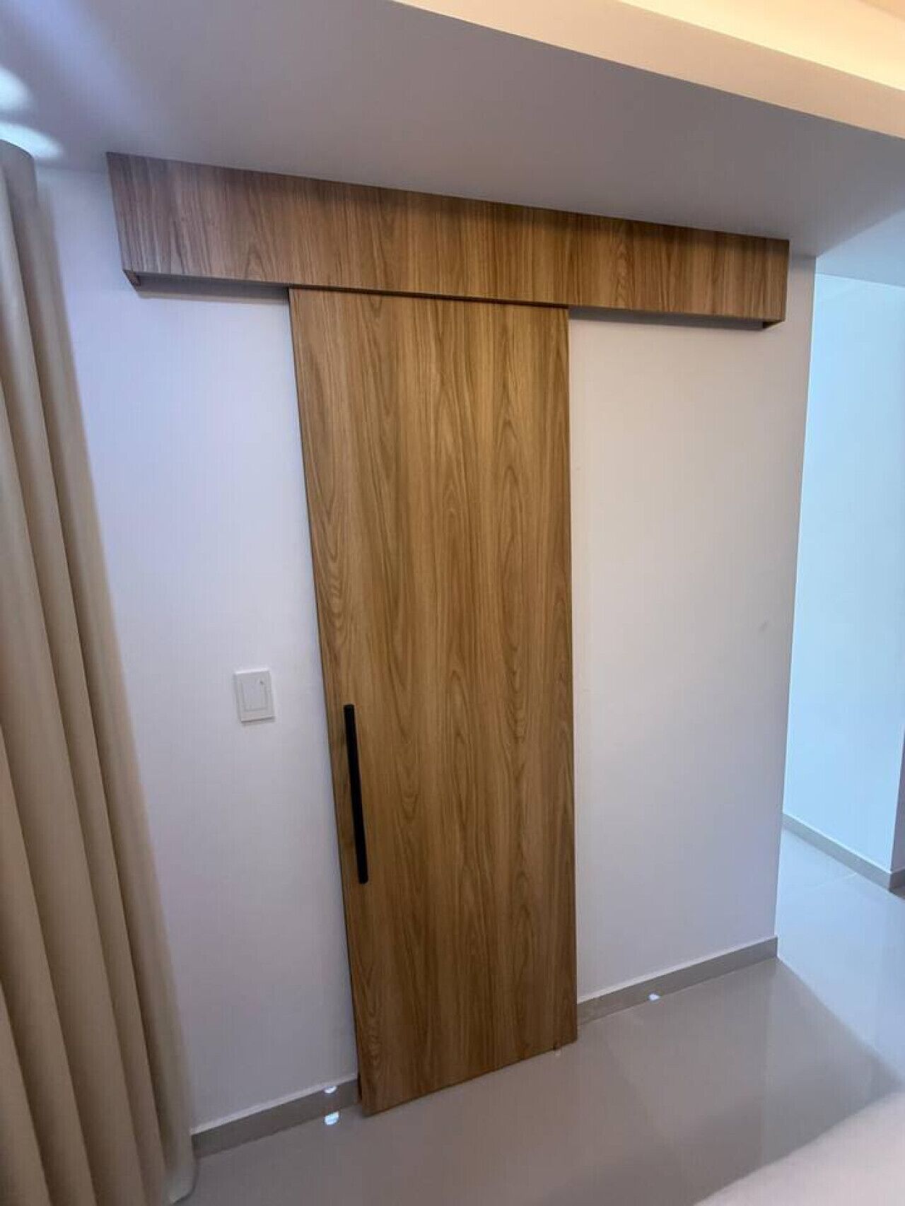 A modern room with a sliding wooden door and a light switch on the wall.