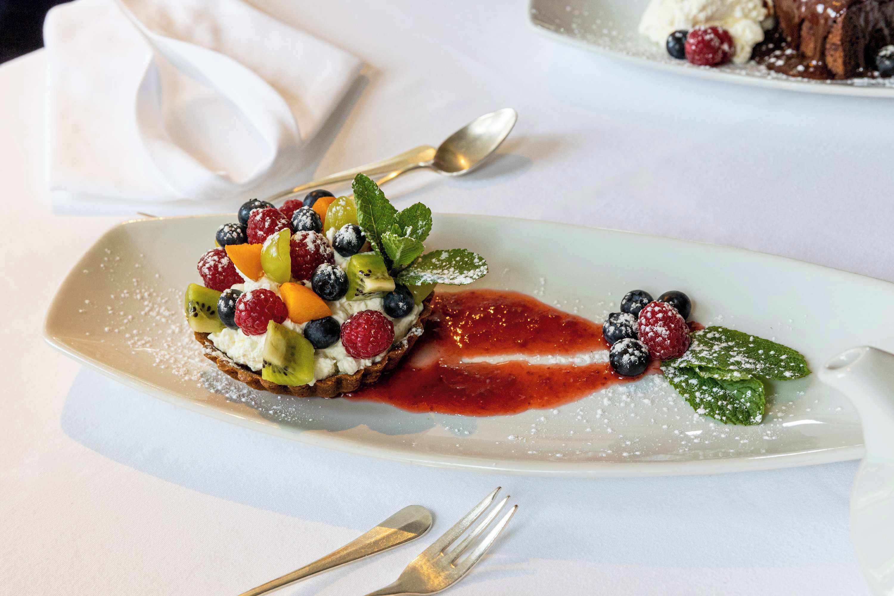 Une assiette de dessert avec un assortiment de fruits et une sauce.