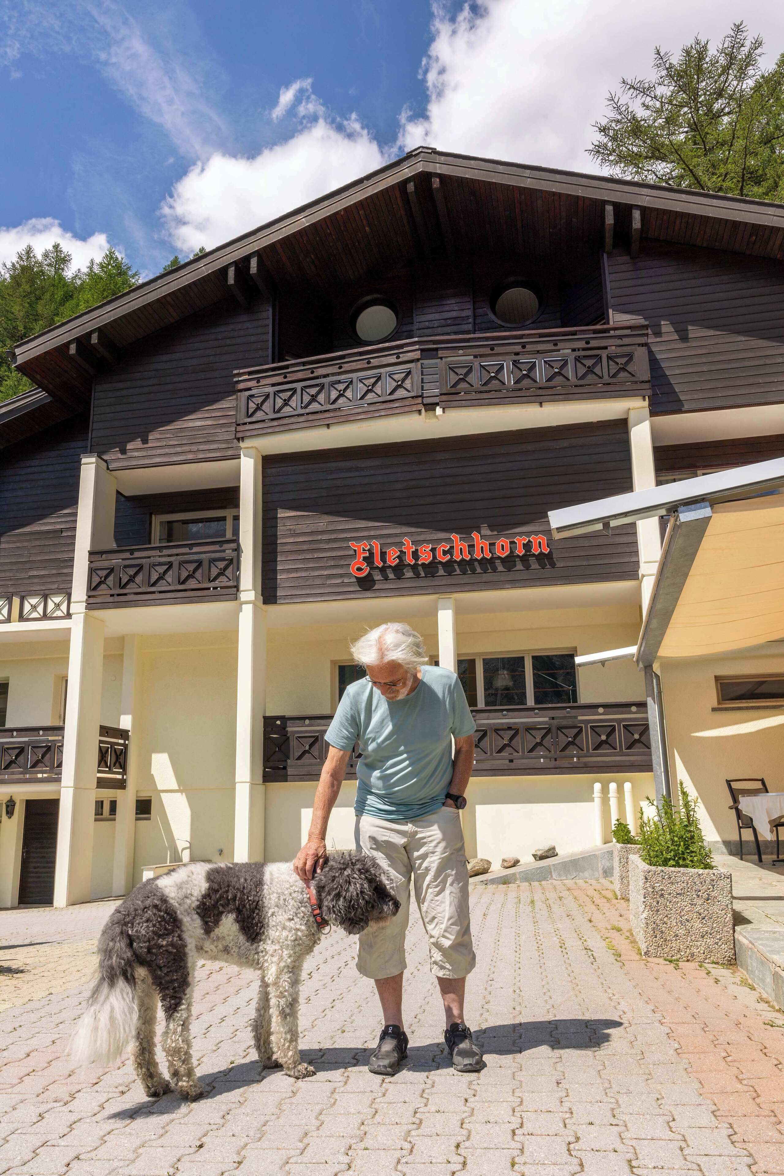 A building with a sign reading "Fleischhorn" and a person with a dog in front.