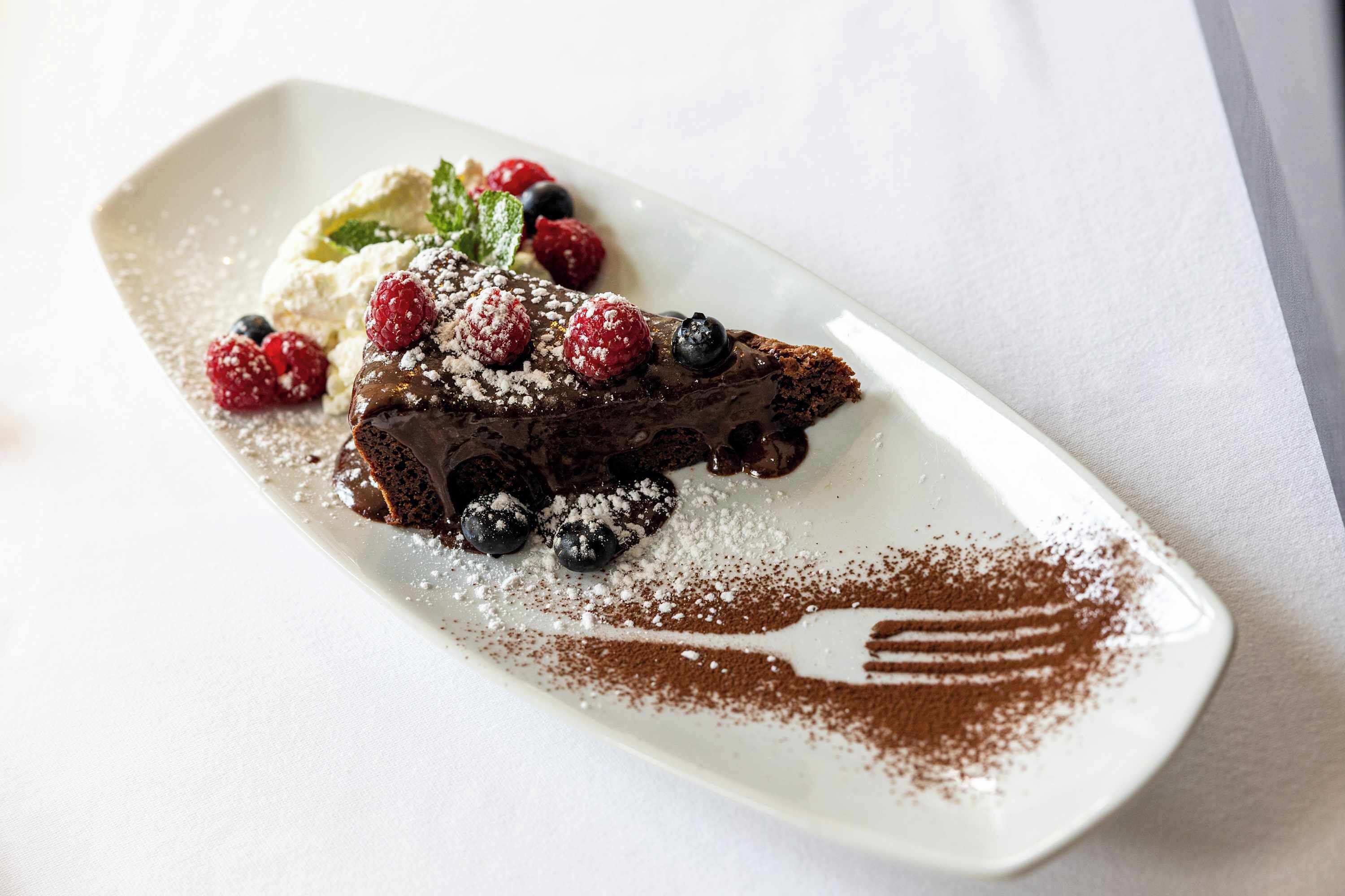 Ein Dessertteller mit Schokoladenkuchen, Beeren und Puderzucker.