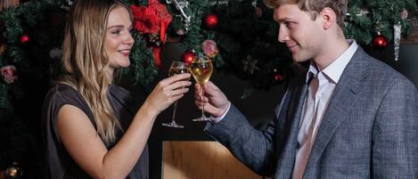 Two people toasting with champagne glasses in front of a Christmas tree.