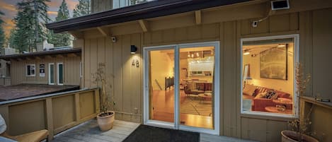 Una cabaña acogedora con terraza, puertas corredizas que dan a una sala de estar con chimenea y vistas del bosque circundante.