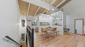 A spacious kitchen with wooden flooring, a dining area with a wooden table and benches, and a staircase with a railing. - Golden Mountain Chalet by Avantstay Incline Village Stay + Minutes to Lake Tahoe, Skiing + Scenic Trails (Incline Village)