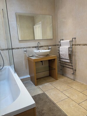Ein Badezimmer mit Badewanne, Waschbecken, Spiegel, Handtuchhalter und einer Duschkabine.