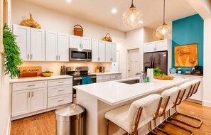 A modern kitchen with white cabinetry, stainless steel appliances, and a central island with bar stools. - Honky Tonk Haven | 13 Beds•5 Baths• Game Room! (Nashville)