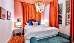 Une chambre à coucher avec un lit, des lampes de chevet, un miroir et une fenêtre avec des stores.