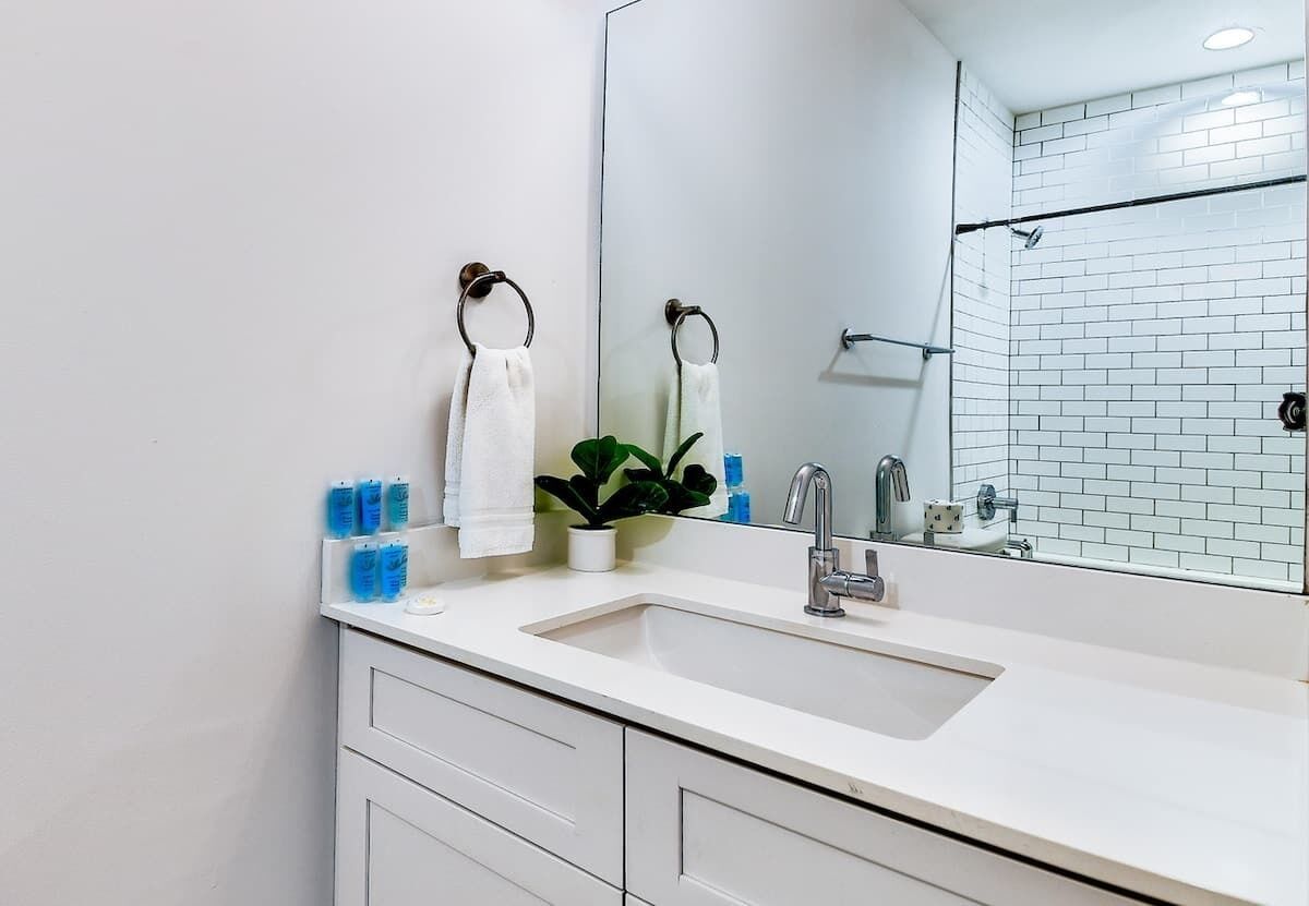 A modern bathroom with a white sink, a large mirror, and a shower area.