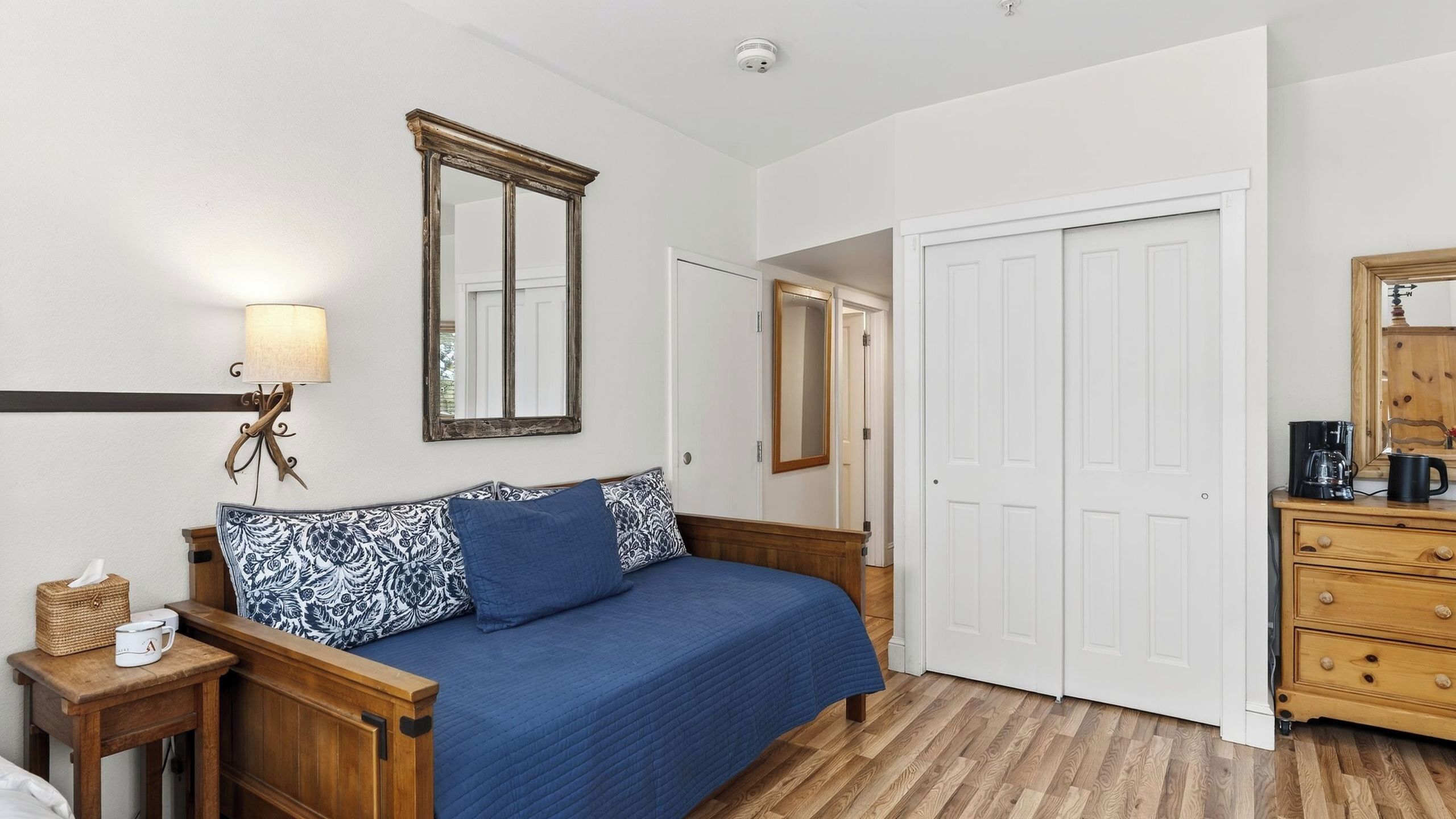 A bedroom with a bed, a dresser, a mirror, and a lamp.