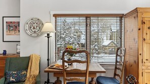 Ein Essbereich mit einem Holztisch, Stühlen, einer Vase mit Blumen und einem Fenster mit Jalousien.