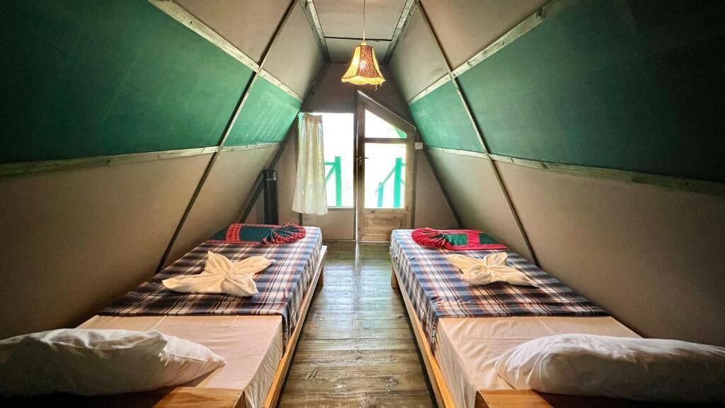 A small, triangular attic room with two beds, each with plaid bedding and pillows.