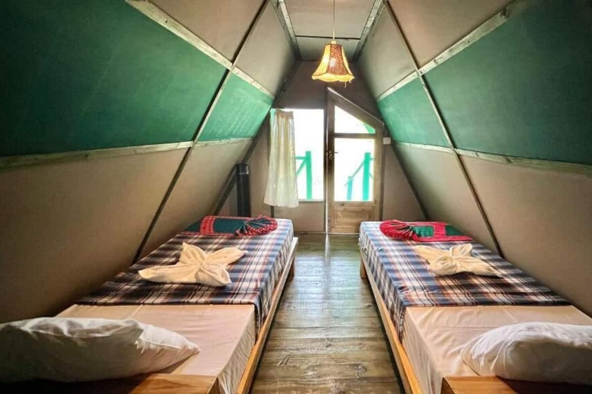 A small, triangular attic room with two beds, each with plaid bedding and pillows.