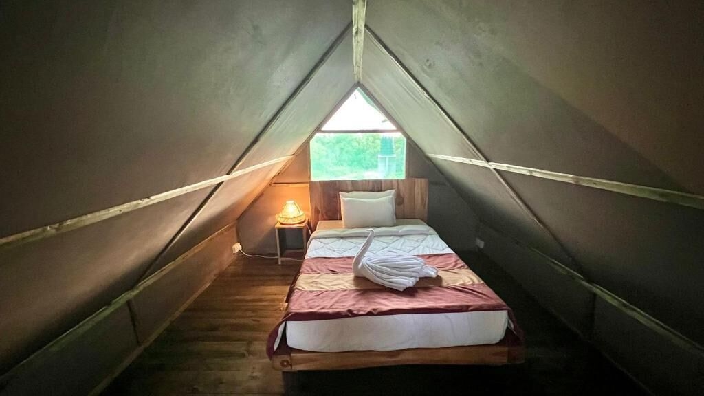 A small, cozy tent with a single bed, a nightstand, and a window.