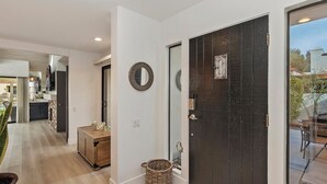 A hallway with a dark wooden door, a round mirror, and a wicker basket. - STUNNING FURNISHED POOLSIDE HOME AT MISSION HILLS COUNTRY CLUB RANCHO MIRAGE (Rancho Mirage)