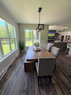 A dining area with a wooden table and chairs, a potted plant, and a view of the outdoors. - A Private Retreat Near Road America, Walk to Downtown Elkhart Lake, Sleeps 12 (Elkhart Lake)