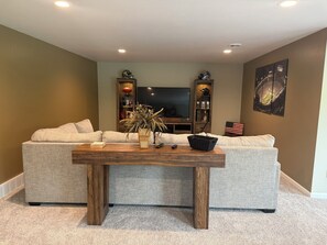 Una sala de estar con un juego de sofá, una mesa de centro de madera, una televisión y un cuadro en la pared.