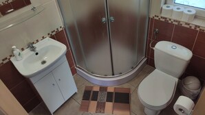 Ein Badezimmer mit Dusche, Toilette, Waschbecken und Spiegel.