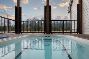 A pool with a view of mountains, a wooden deck, and a metal fence. - Door to Door Two Condos in Harive Height (Harvie Heights)