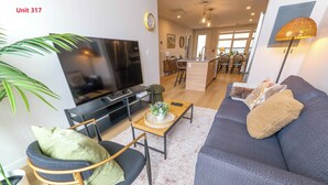 A modern living room with a sofa, TV, and dining area.