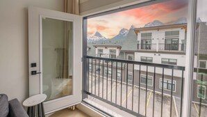 A room with a large window overlooking a mountain landscape, a sliding glass door, and a small table.