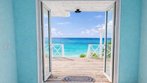 Ein Zimmer mit Blick auf das Meer durch eine Glasdoor, Holzboden und eine strukturierte Matte in der Mitte.