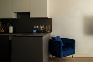 Une cuisine moderne avec un plan de travail foncé, une chaise bleue et un design minimaliste.