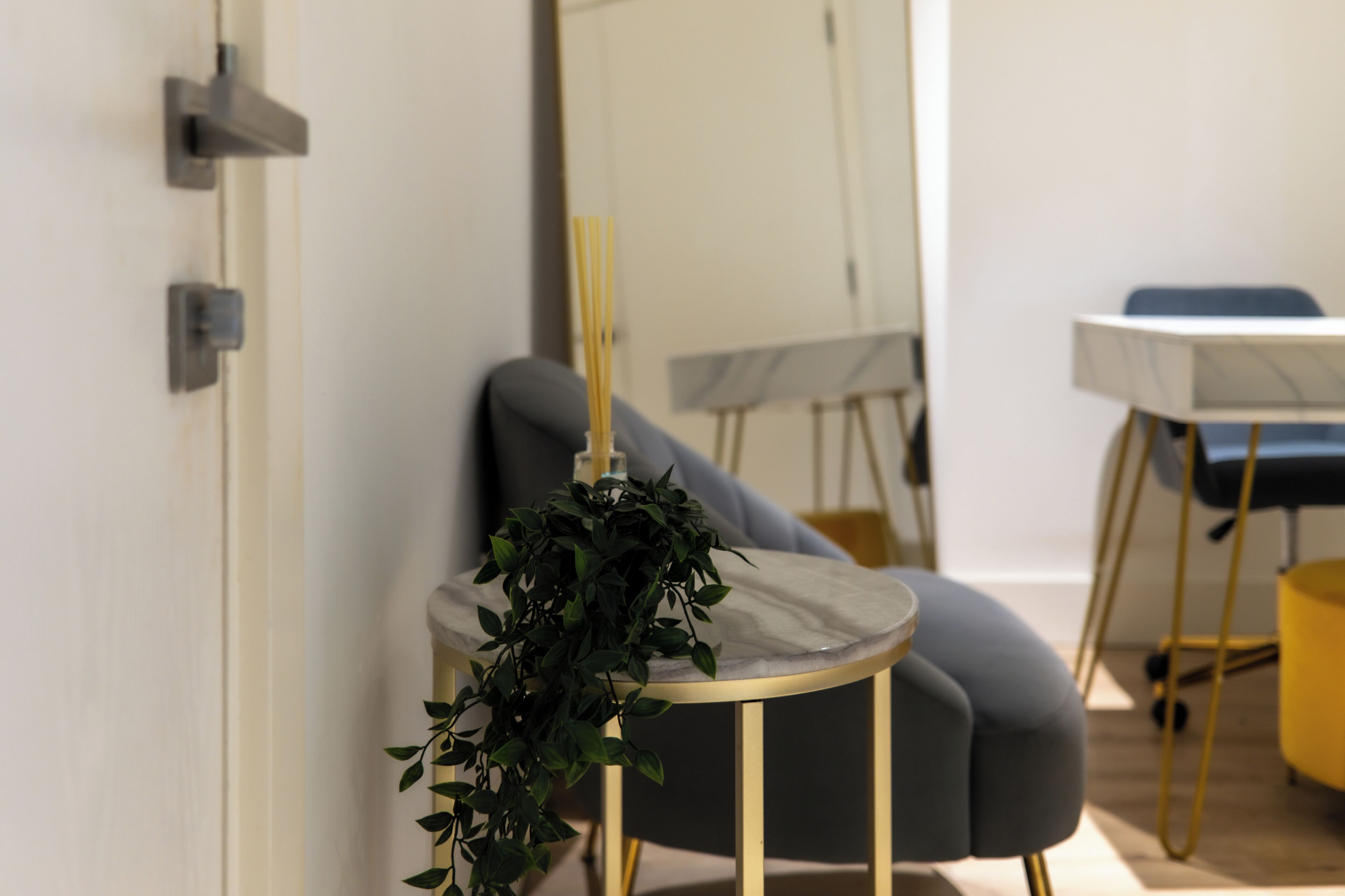A modern room with a round table, a grey armchair, and a small side table with a plant.