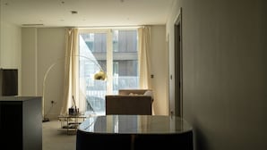 Ett modernt hotellrum med ett stort fönster, ett runt bord, en soffa och en golvlampa.