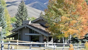 A house with a porch, a fenced yard, and a mountain backdrop. - Private 4 Bedroom 4 Bath Sun Valley Getaway. Hot Tub/Large Yard/ Dog Friendly (Sun Valley)
