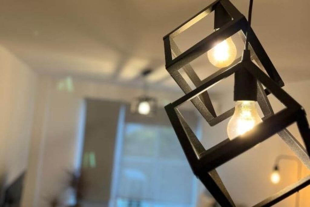 Un intérieur moderne avec des luminaires aux formes géométriques et une porte visible au fond.