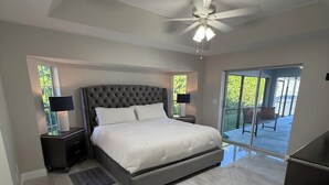 A spacious bedroom with a large bed, a ceiling fan, and a view of a balcony. - Stunning 4 bedroom home with Heated Pool and Spa (Cape Coral)