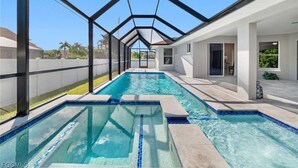A swimming pool with a glass ceiling, surrounded by a white building with a modern design. - Stunning 4 bedroom home with Heated Pool and Spa (Cape Coral)