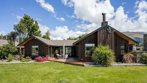 Een modern huis met een houten gevel, een ruim terras en een verzorgd gazon.
