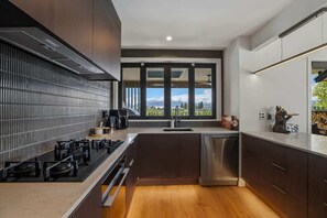 A modern kitchen with a stove, sink, and dishwasher. - The Wanaka Luxe Pool House - Sleeps 10 (Wānaka)