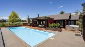 Een zwembad met een overdekte patio, een jacuzzi en een stenen openhaard.