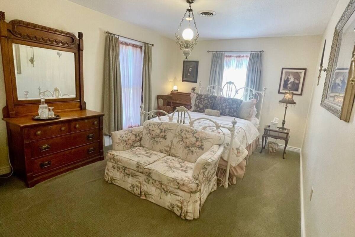 Un dormitorio con cama, cómoda, sofá, candelabro y espejo.