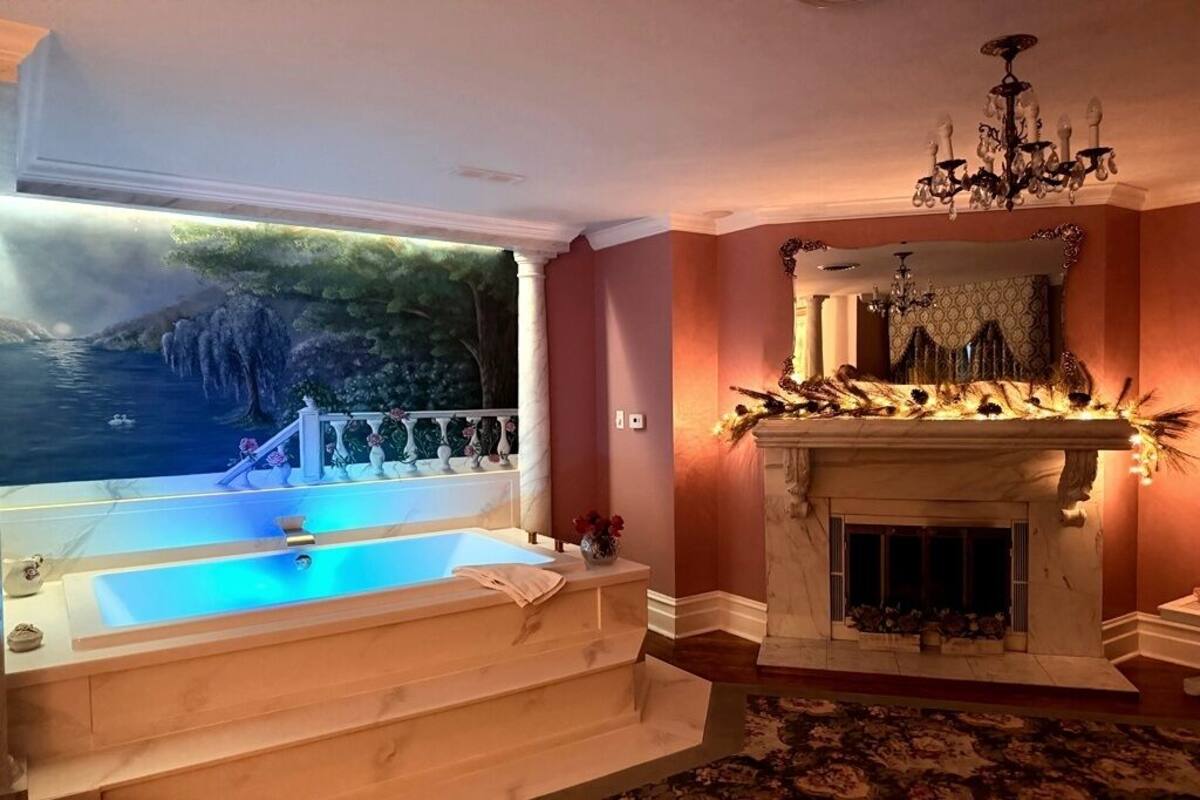 Una habitación con una bañera grande, una chimenea y un mural de una cascada.