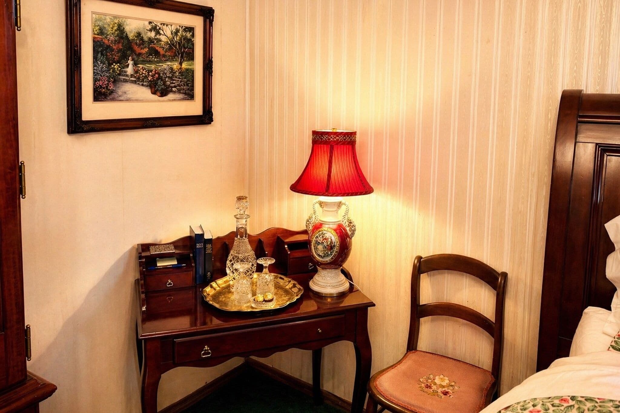 A wooden desk with a lamp, a framed picture, and a chair in a hotel room.