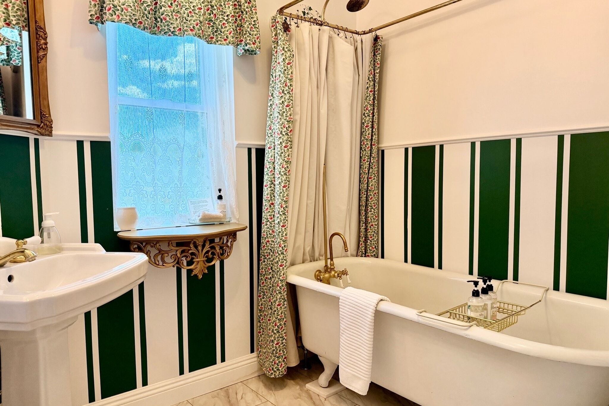 A bathroom with a bathtub, sink, and window with curtains.
