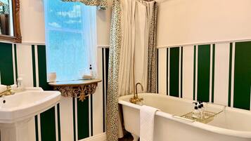 A bathroom with a bathtub, sink, and window with curtains.