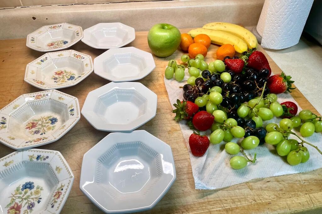 Un comptoir de cuisine avec différentes assiettes, une planche à découper avec des fruits et un rouleau d’essuie-tout.