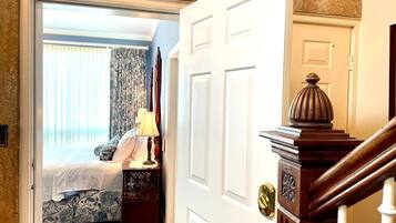 A bedroom with a bed, a nightstand, a lamp, and a view of the outside.