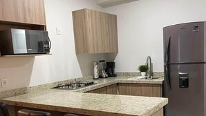 Eine moderne Küche mit Granit Arbeitsplatte, Edelstahlgeräten und schwarzen Barhocker.