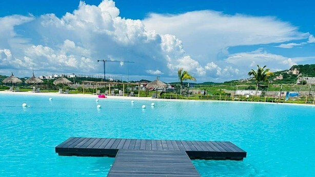 Ein hölzerner Infinity-Pool mit blauem Himmel und weiter Landschaft im Hintergrund.