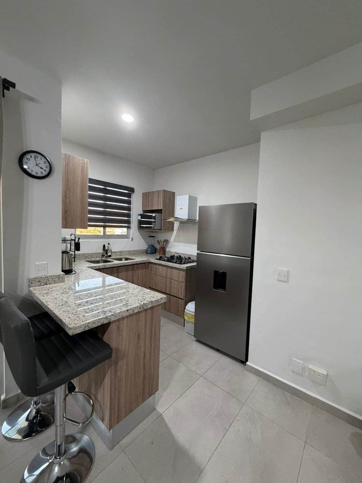 Una cocina moderna con una isla central, electrodomésticos de acero inoxidable y armarios de madera.