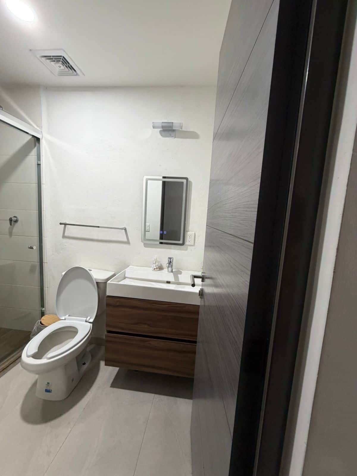 A modern bathroom with a toilet, sink, and mirror.