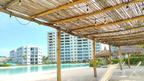 Ein Strandresort mit Pool, Liegestühlen und einer Struktur mit Reetdach.