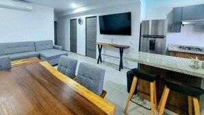 A modern kitchen with a built-in oven, a stainless steel refrigerator, and a flat-screen TV mounted on the wall. - 3-bedroom apartment with lagoon and beach views (Mazatlán)