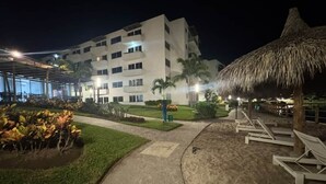 A hotel with a pool area, a covered walkway, and a thatched-roof structure. - Lagoon view apartment plus exclusive amenities (Mazatlán)